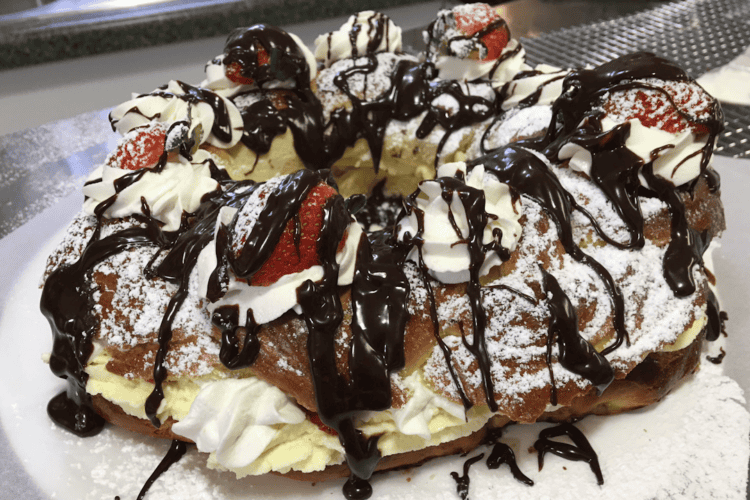 Strawberry dessert ring with whipped cream, powdered sugar, and chocolate drizzle